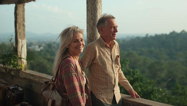 Mature couple enjoying scenic valley view at golden hour, traveling retirees