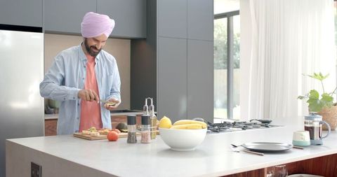 Man in Turban Slicing Avocado in Modern Kitchen for Healthy Meal