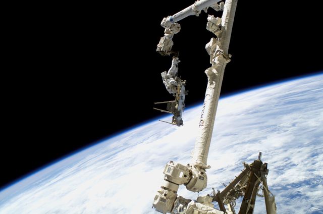 Astronaut performing a spacewalk attached to the Canadarm2 with Earth’s horizon in the background. Ideal for space exploration, scientific research, and aerospace engineering concepts. Suitable for educational materials, documentaries, and space mission presentations.