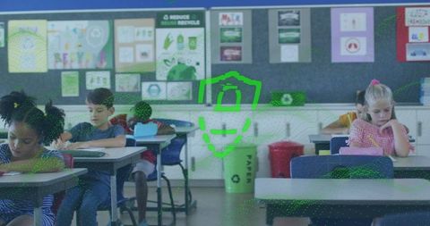 Elementary students writing at desks with recycling bin and colorful classroom posters