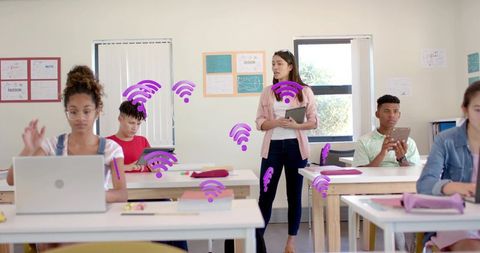 Teacher guiding digital classroom with students using laptops and tablets, wi-fi concept