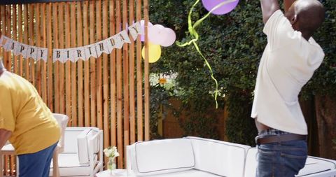 Family Prepares Outdoor Birthday Celebration with Banners and Balloons