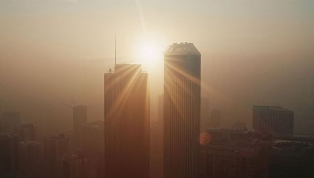 Dramatic sunrise piercing through smoggy city skyline