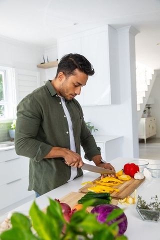 Man Slicing Yellow Bell Pepper in Bright Modern Kitchen