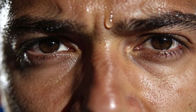 Gazing man with furrowed brow and sweat droplet highlighting skin texture