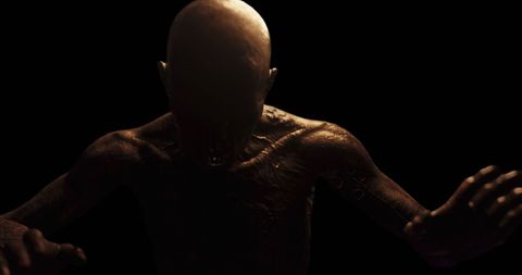 Terrifying Bald Figure with Distorted Features in Shadowy Darkness