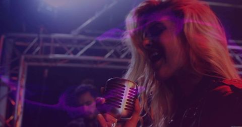Energetic Female Vocalist Singing into Vintage Microphone on Stage with Pink Haze