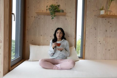 Woman Relaxing at Home with Tea on Tranquil Daybed by Windows