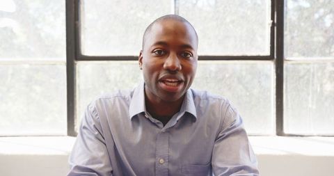 Confident Businessman in Blue Shirt at Bright Office Desk