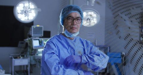 Surgeon preparing for surgery in modern operating room with patient monitors