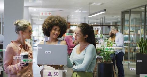 Women Colleagues Collaborating with Laptop in Modern Office Space
