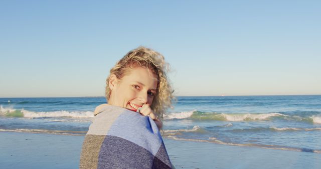 Smiling Woman Wrapped in Blanket on Sunny Beach - Download Free Stock Images Pikwizard.com