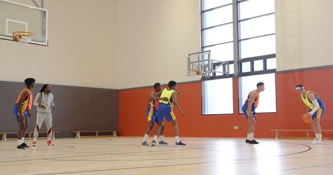 Basketball team performing drills in indoor gym with coach