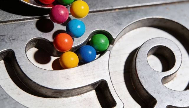 Glossy multicolor gumballs nestling in machined metal groove macro abstract composition