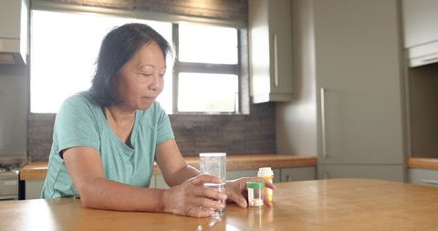Senior Woman Analyzing Medication in Kitchen for Wellness