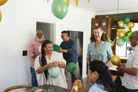 Multigenerational group decorating kitchen with green gold balloons, joyful gathering
