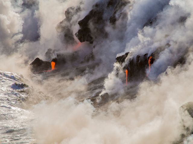 Shows the dramatic scene of lava flowing from a volcano into the ocean, creating large amounts of steam and mist. Ideal for use in educational materials about volcanic activity, geological phenomena, and natural science presentations. Can also be used in travel and tourism promotions to showcase the appeal of volcanic islands like Hawaii.