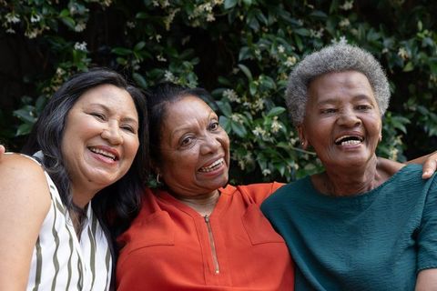 Multicultural senior women laughing together outdoors embracing friendship and joy