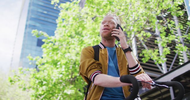 Young man riding bicycle while talking on phone in urban setting - Download Free Stock Images Pikwizard.com