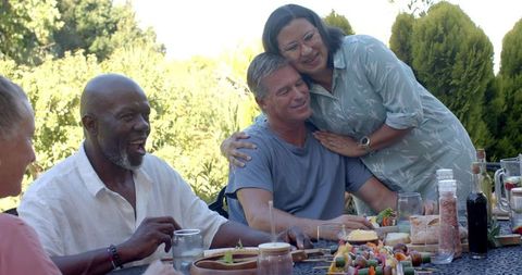 Diverse group enjoying outdoor meal with laughter and affection