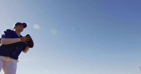 Teen Baseball Player Preparing to Catch Ball Against Clear Sky