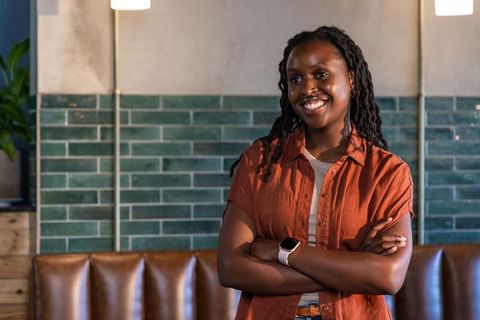 Confident african american woman smiling in cafe wearing rust shirt and smartwatch