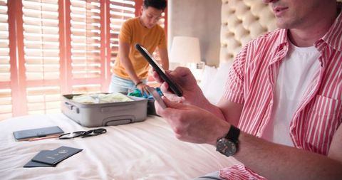 Diverse couple packing and planning travel with smartphone
