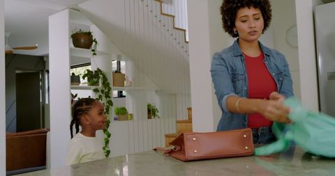 Mother and Daughter Unpacking Backpack at Kitchen Island