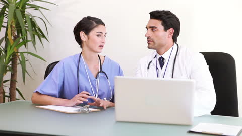 Doctors Collaborating in Office with Laptop for Medical Discussion