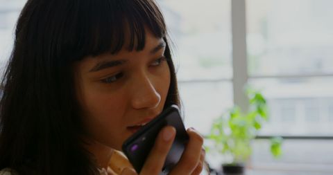 Woman Speaking on Mobile Phone in modern office with Dim Lighting