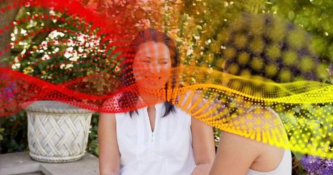 Woman sitting on garden bench in white top with vibrant red-yellow dotted wave overlay