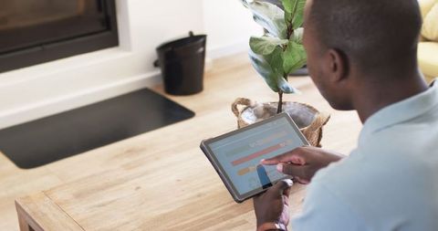 Man monitoring home energy usage on tablet in relaxed setting