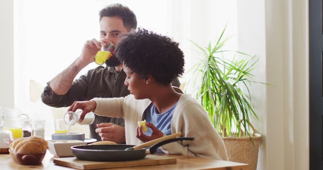 Couple enjoying breakfast together in a sunlit kitchen, creating a warm and casual atmosphere. Use this for themes related to home life, relationships, morning routines, or food and drink.