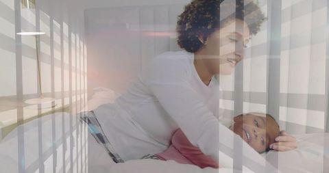 Mother and daughter cuddling on bed with soft window light and lamp reflections