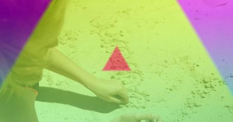 Child tracing letters in beach sand with colorful neon gradient overlay, triangle accent