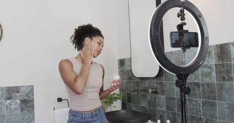 Beauty influencer filming skincare routine at vanity with ring light and smartphone