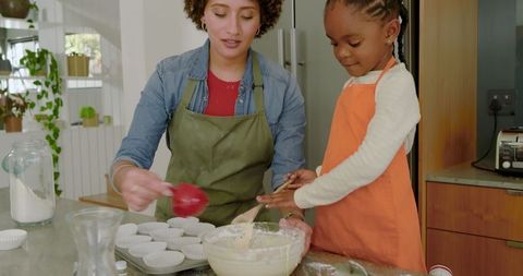 Mother and daughter baking muffins together at home
