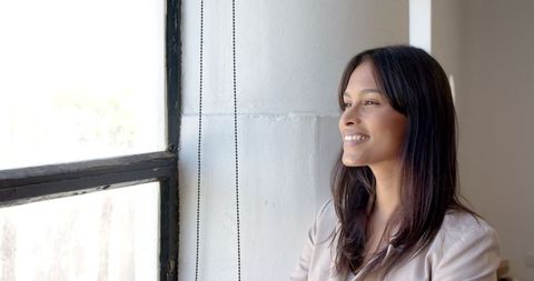 Smiling Businesswoman Looking Out Window for a Relaxing Work Break
