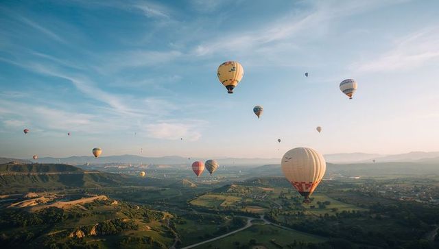 Hot air balloons soaring over scenic valley at dawn