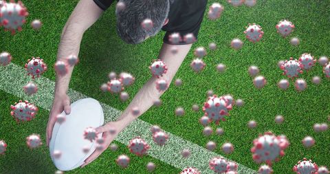 Rugby player landing large ball on field with virus simulation overlay