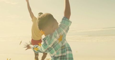 Sunlit beach running child in green plaid shirt with gold star confetti overlay