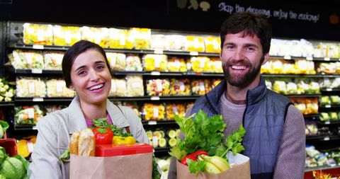 Happy couple shopping for organic produce in supermarket