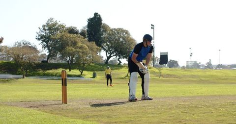 Male cricketer in action on sunny day at outdoor field