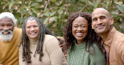Diverse multigenerational family laughing and smiling outdoors in cozy knit sweaters