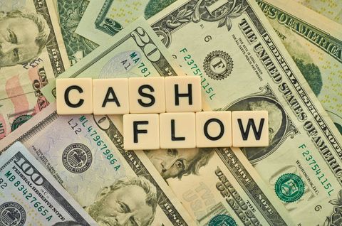 Cash Flow Concept with Scattered US Dollar Bills and Letter Tiles