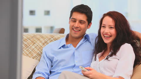 Happy Couple Relaxes on Couch Watching Television