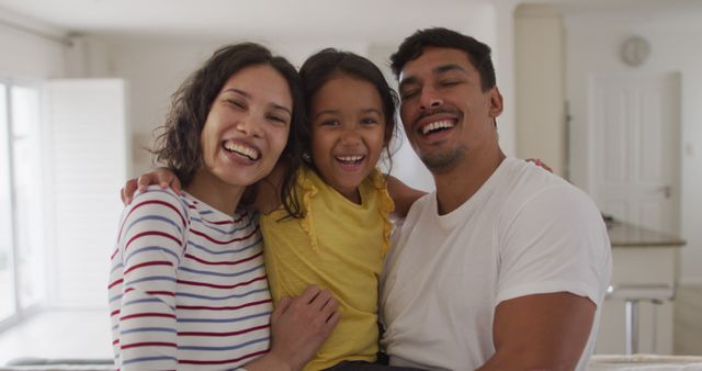 Portrait of happy hispanic parents and daughter standing embracing. at home in isolation during quarantine lockdown.