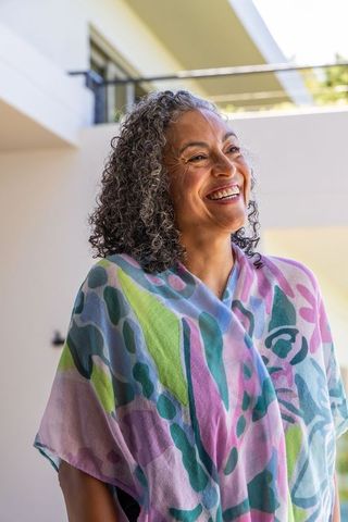 Senior african american woman smiling on balcony wearing colorful pastel shawl