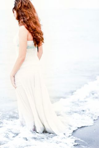 Woman in elegant dress enjoying ocean waves