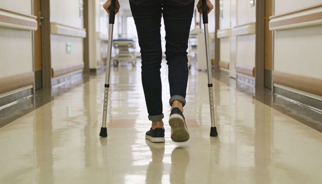 Patient Walking with Forearm Crutches in Hospital Corridor Demonstrating Mobility Recovery